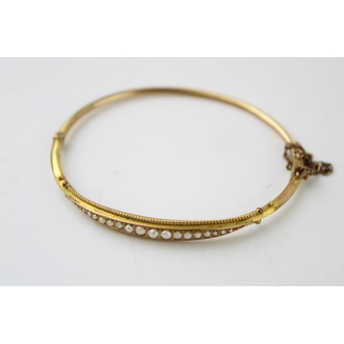 323 - A yellow metal lady's bangle, tests as 9ct or better, set graduated seed pearls, in period fitted bo... 