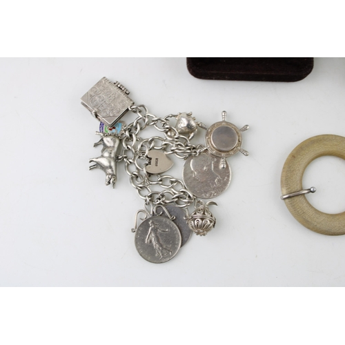 351 - A group of silver comprising a silver cased small scent bottle and funnel, a silver charm bracelet w... 