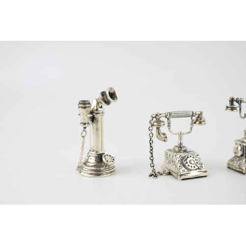 356 - A collection of silver jewellers toys in the form of telephones. (3) 52g.