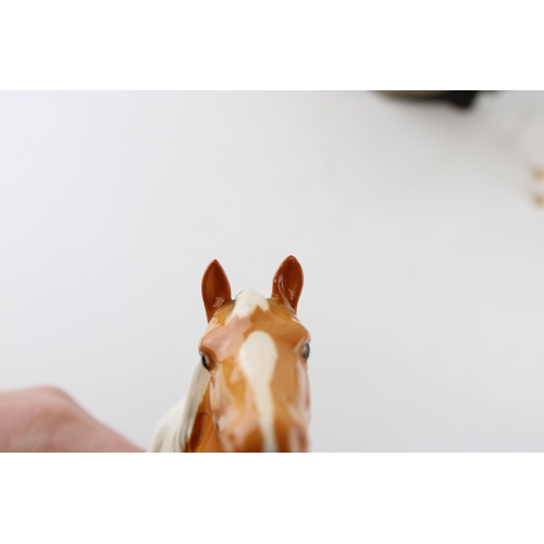 246 - Two Beswick palomino horses (1 ear af) and a large Royal Doulton character jug The Falconer (3).