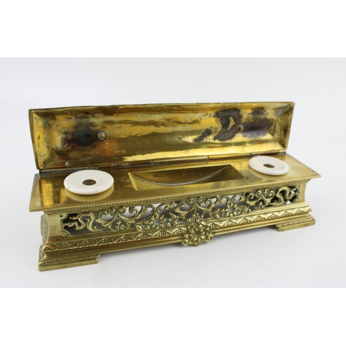 265 - An ornate brass ink stand with original ceramic liners. Width 25cm, height 8cm.