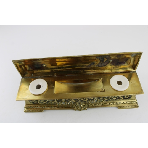 265 - An ornate brass ink stand with original ceramic liners. Width 25cm, height 8cm.