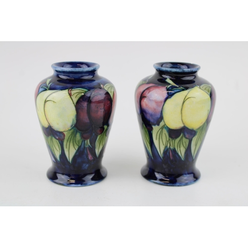 60 - Two Moorcroft Wisteria Plum vases, both chipped, 9.5cm tall.