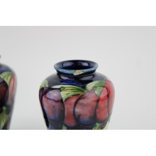 60 - Two Moorcroft Wisteria Plum vases, both chipped, 9.5cm tall.