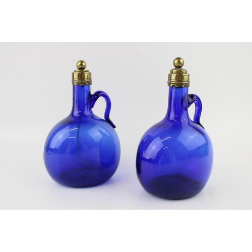 296 - A pair of Victorian Bristol blue glass decanters, curved handles, brass stopper and rims, 20.5cm tal... 