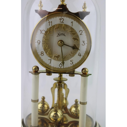 331 - An anniversary clock by Koma with brass enamelled base and glass dome. Dial decorated with signs of ... 