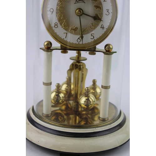 331 - An anniversary clock by Koma with brass enamelled base and glass dome. Dial decorated with signs of ... 