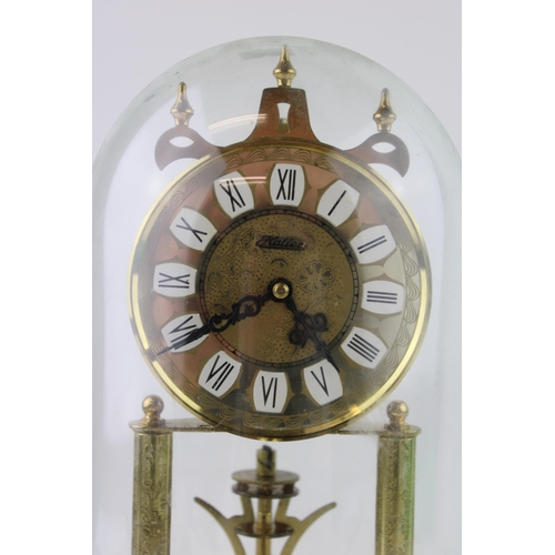 333 - An anniversary clock by Haller with brass base and glass dome. White brass dial with Roman numerals.... 