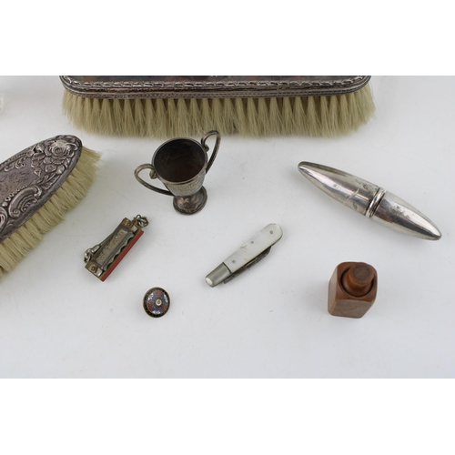 552 - A collection of early c20th sterling silver brushes, a small trophy, silver blade fruit knife and bo... 