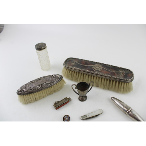 552 - A collection of early c20th sterling silver brushes, a small trophy, silver blade fruit knife and bo... 