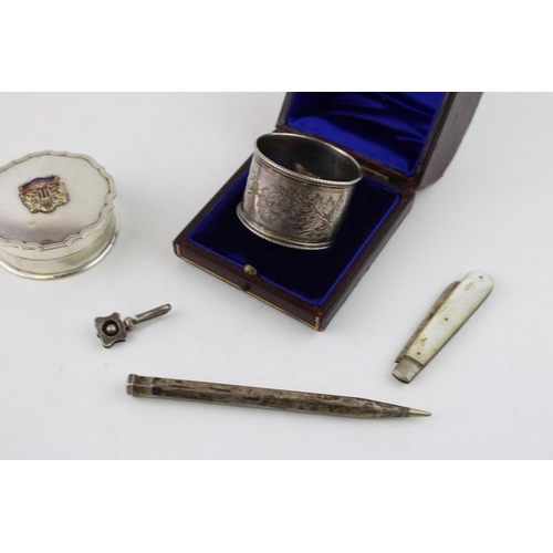 557 - A collection of silver items to include napkin ring, menu holder, SS Oronsay pill box, a silver blad... 