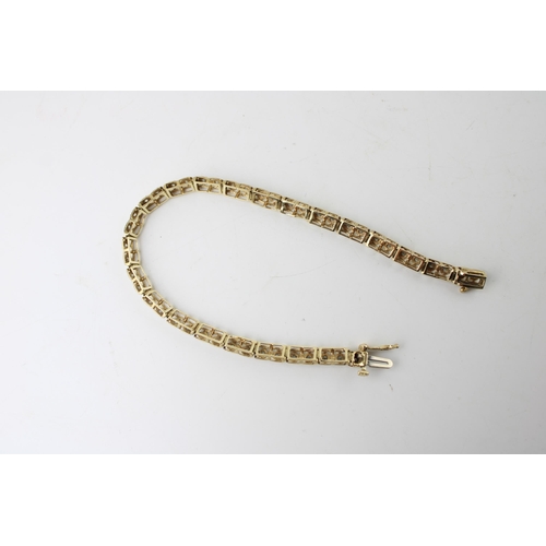 423 - A 10ct gold and diamond tennis bracelet, of twenty two panels each set with two diamonds, 6.4g, 18cm... 