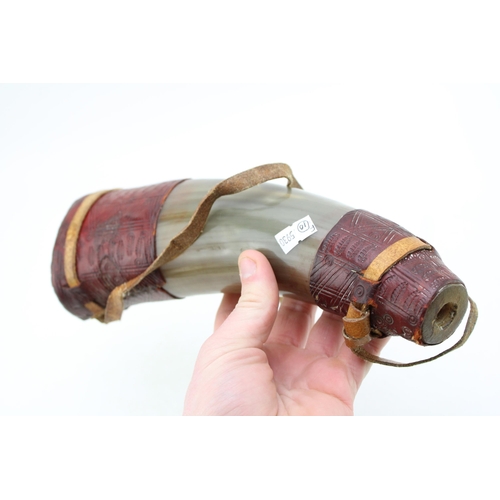 450 - An antique horn powder flask with turned horn stopper and shoulder strap with inscribed leather deco... 