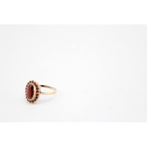 651 - A 9ct gold and garnet dress ring, the oval cut central stone of approximately6 9.5 by 5.0mm, surroun... 