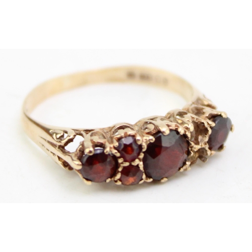 656 - A 9ct gold and garnet three stone ring, each garnet  interspersed with pair of further garnet brilli... 