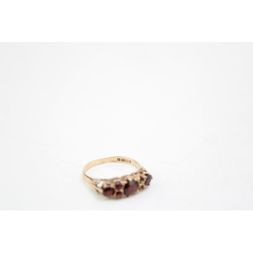 656 - A 9ct gold and garnet three stone ring, each garnet  interspersed with pair of further garnet brilli... 