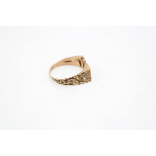 663 - A 9ct gold mid century brutalist design signet ring, the central emblem of initials 'PM', with bark ... 