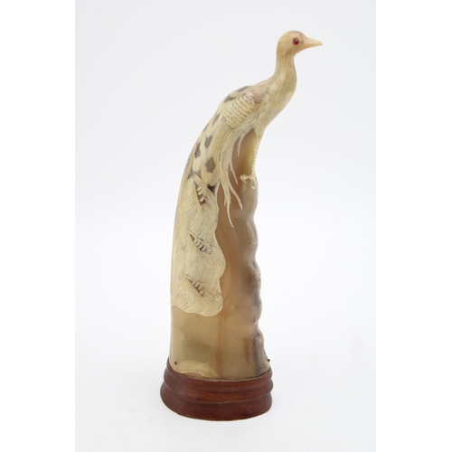 107 - A carved horn figure of a peacock mounted on wooden plinth. Height 31.5cm.