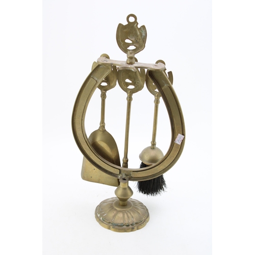 144 - A brass fireside companion set in the form of a horseshoe. Height 45cm.