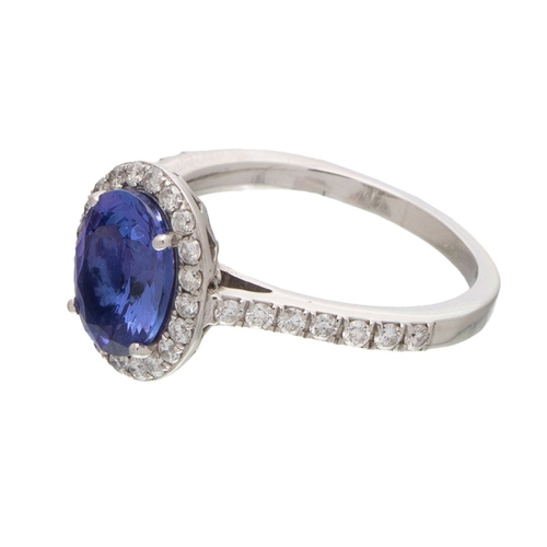 223 - A tanzanite and diamond halo platinum ring, the central tanzanite oval cut stone of approximately 9.... 