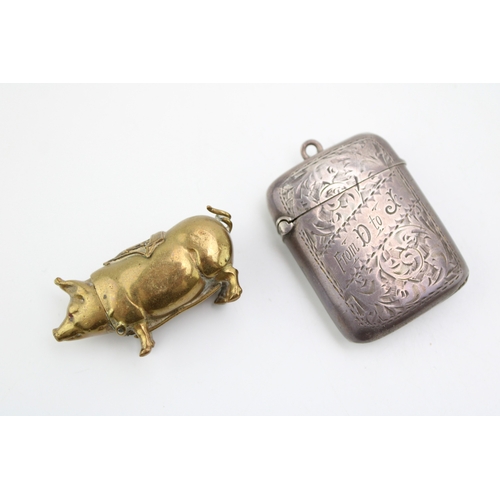 196 - A brass pig vesta case wit hinged head, sailing ship saddle and strike to the belly, together with a... 