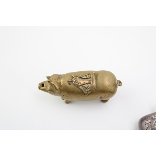 196 - A brass pig vesta case wit hinged head, sailing ship saddle and strike to the belly, together with a... 