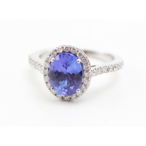 223 - A tanzanite and diamond halo platinum ring, the central tanzanite oval cut stone of approximately 9.... 