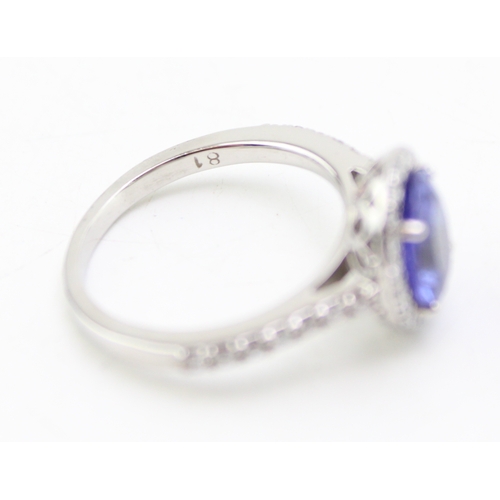 223 - A tanzanite and diamond halo platinum ring, the central tanzanite oval cut stone of approximately 9.... 