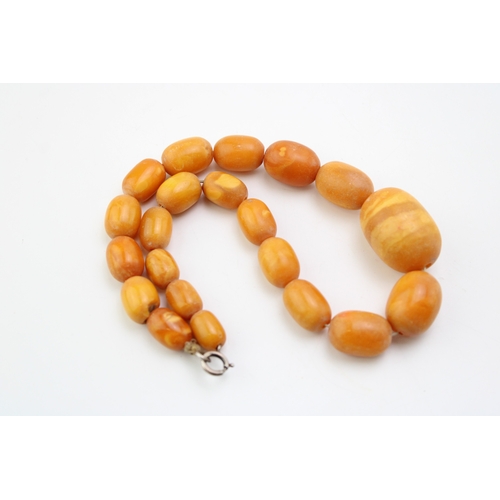 265 - A string of vintage butterscotch opaque amber beads, of graduated oval form, largest bead with disti... 