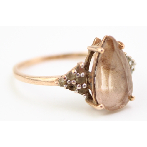 461 - A 9ct gold and quartz dress ring set with central pear cut smokey quartz with white stone highlights... 