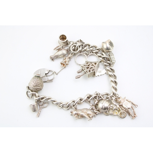 484 - A silver curb link charm bracelet with heart shaped padlock clasp, and fourteen charms, including ca... 