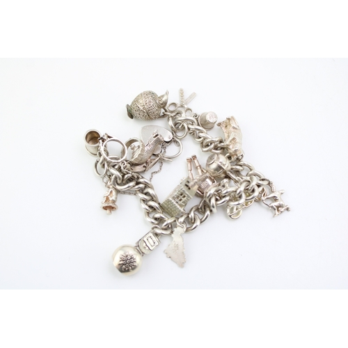 484 - A silver curb link charm bracelet with heart shaped padlock clasp, and fourteen charms, including ca... 