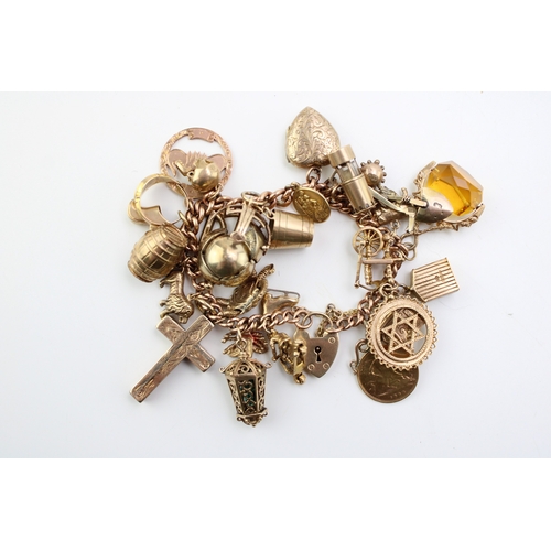 503 - A 9ct gold curb link charm bracelet with twenty seven charms, including a half sovereign, Queen Vict... 