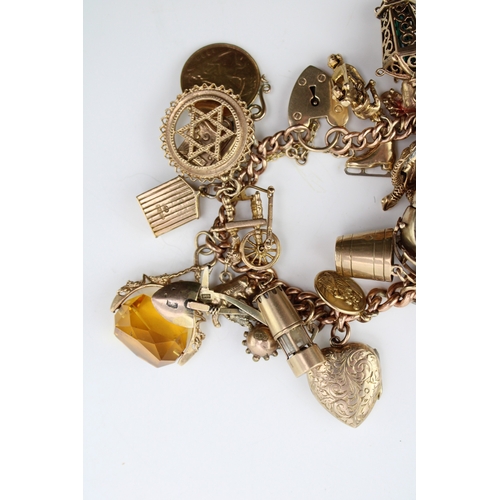 503 - A 9ct gold curb link charm bracelet with twenty seven charms, including a half sovereign, Queen Vict... 