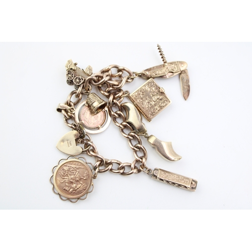 504 - A 9ct gold charm bracelet with heart shaped padlock clasp and eight charms comprising 1909 gold half... 