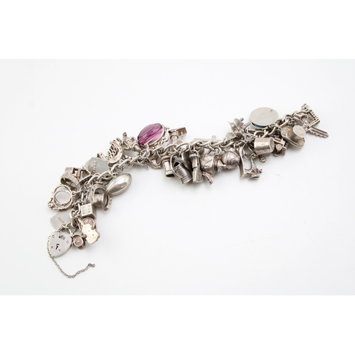 505 - A silver curb link charm bracelet with a large number of charms including a rugby ball, elephant, gr... 