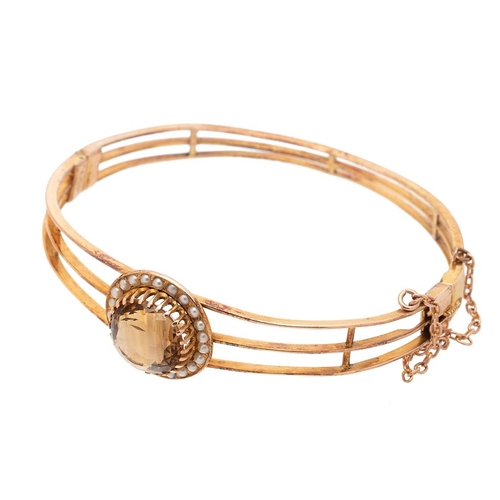 253 - An Art Deco, gold, citrine and pearl set bangle, the citrine of approximately 18.3mm, encircled by a... 