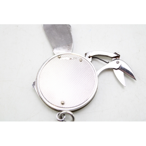 163 - A silver circular fob with integral steel folding manicure set, comprising scissors, file and knife,... 