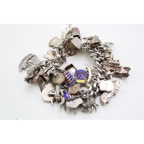226 - A silver curb link charm bracelet, hallmarked to the links, with fourty three charms, in a variety o... 