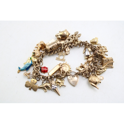 227 - A 9ct gold open double link charm bracelet with heart shaped padlock clasp and thirty six charms, mo... 