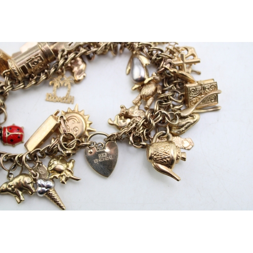 227 - A 9ct gold open double link charm bracelet with heart shaped padlock clasp and thirty six charms, mo... 