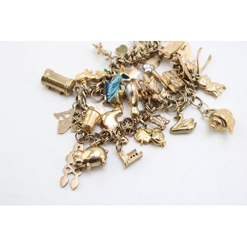 227 - A 9ct gold open double link charm bracelet with heart shaped padlock clasp and thirty six charms, mo... 
