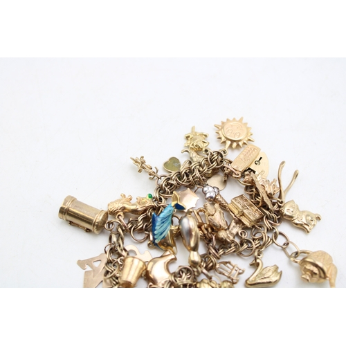 227 - A 9ct gold open double link charm bracelet with heart shaped padlock clasp and thirty six charms, mo... 
