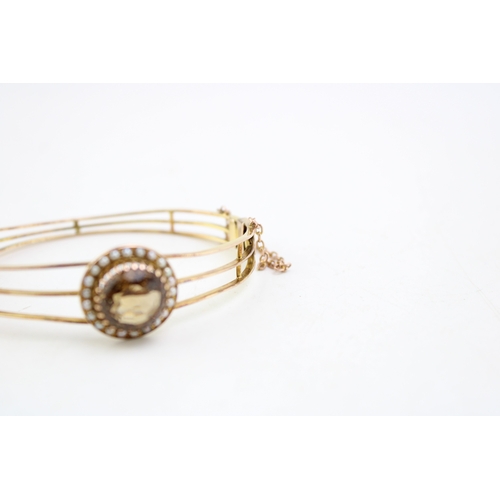 253 - An Art Deco, gold, citrine and pearl set bangle, the citrine of approximately 18.3mm, encircled by a... 