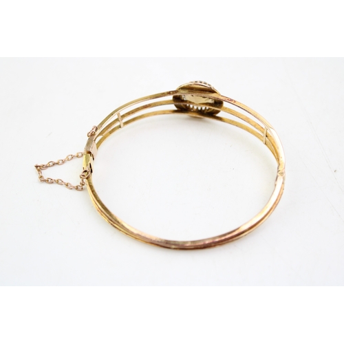 253 - An Art Deco, gold, citrine and pearl set bangle, the citrine of approximately 18.3mm, encircled by a... 