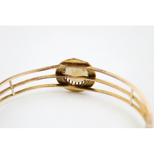 253 - An Art Deco, gold, citrine and pearl set bangle, the citrine of approximately 18.3mm, encircled by a... 