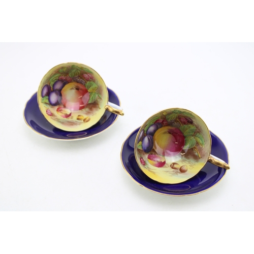 347 - Two Aynsley cups and saucers with fruit scene decoration, on cobalt blue backgrounds, both signed D ... 