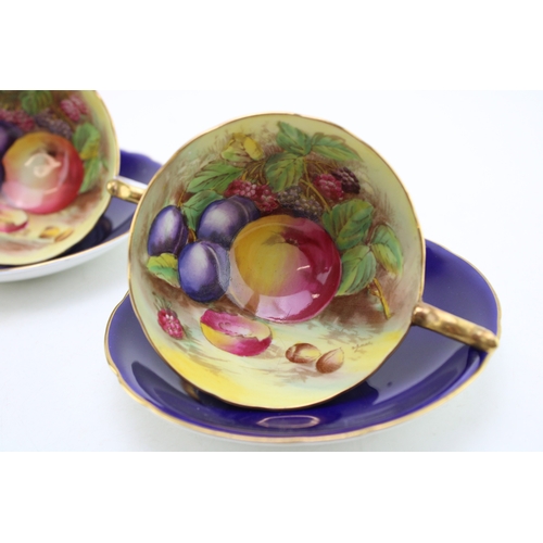 347 - Two Aynsley cups and saucers with fruit scene decoration, on cobalt blue backgrounds, both signed D ... 