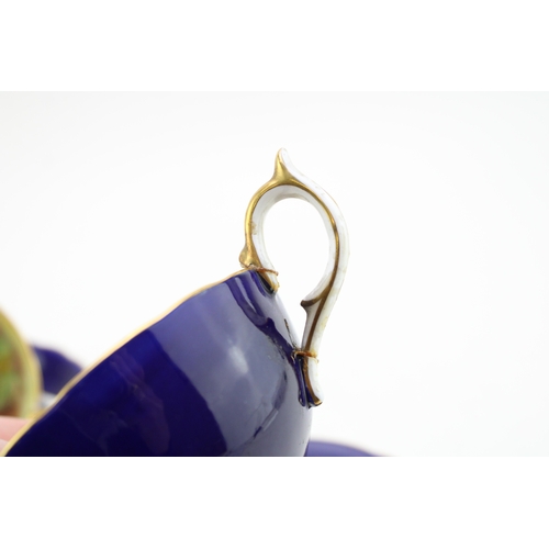 347 - Two Aynsley cups and saucers with fruit scene decoration, on cobalt blue backgrounds, both signed D ... 