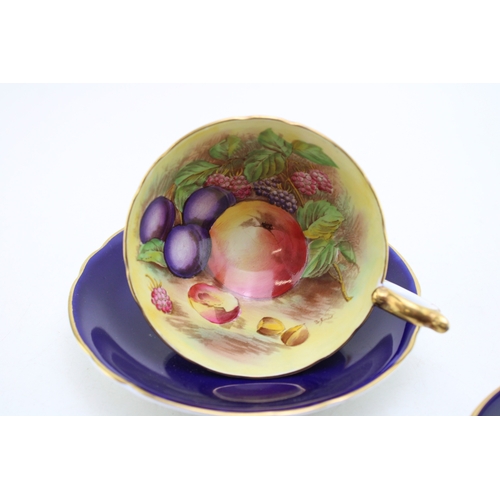 347 - Two Aynsley cups and saucers with fruit scene decoration, on cobalt blue backgrounds, both signed D ... 